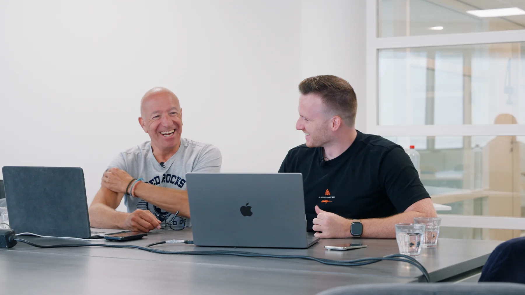 Mika en een klant lachen achter hun laptops tijdens een partnership-sessie